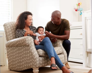 Two adults with a baby in a nursery