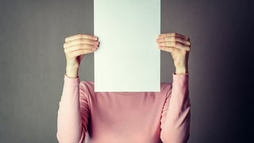 person holding paper in front of their face