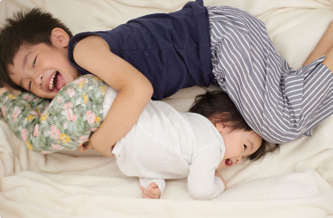 2 kids snuggling on bed
